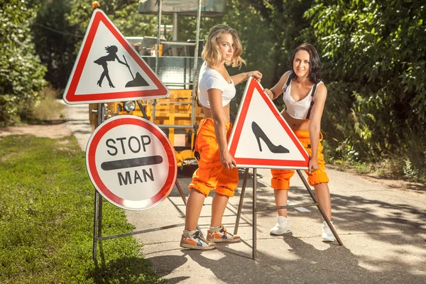 Twee vrouwen in oranje overalls zijn montage "No mannen" borden op de — Stockfoto