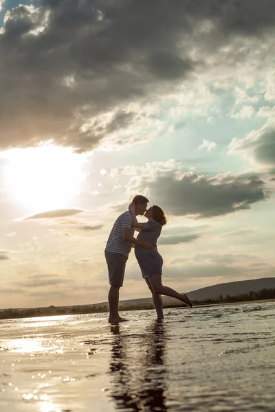 幸せなカップルを水の中に立っているとキス. — ストック写真