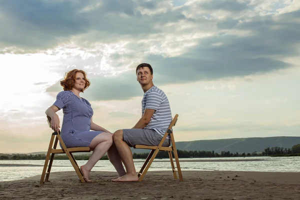 Bella coppia è seduta sulle sedie sul backgroun fiume — Foto Stock