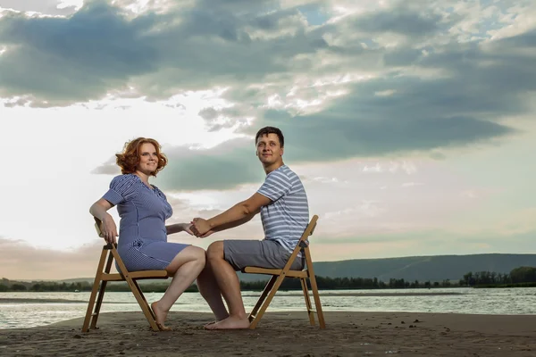 Hermosa pareja está sentada en las sillas en el fondo del río — Foto de Stock