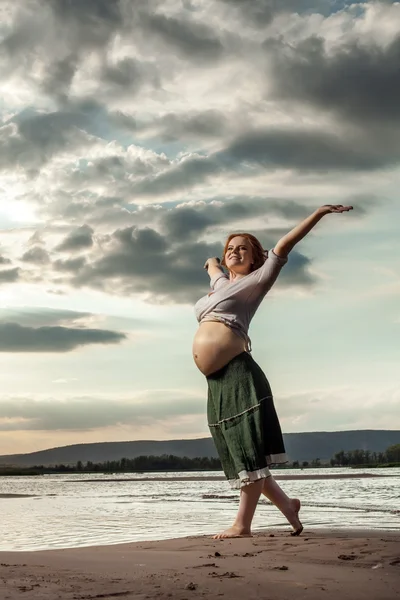 Femme enceinte aux cheveux roux marche sur le fond de la rivière . — Photo