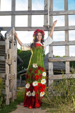 Rus geleneksel elbiseli genç kadın yakınındaki ahşap duruyor