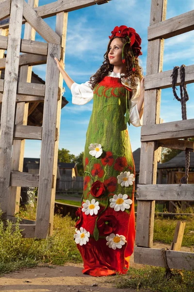 Jovem mulher em russo vestido tradicional está de pé perto de madeira — Fotografia de Stock