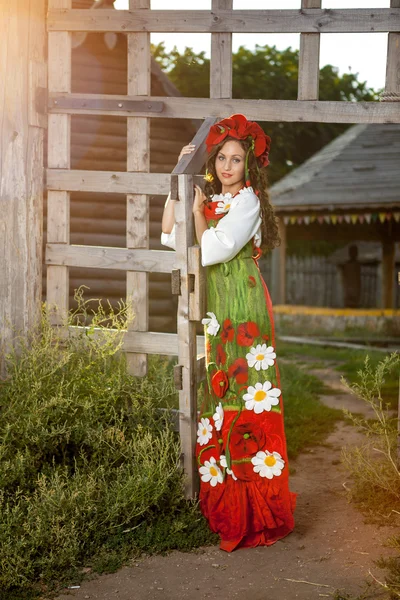 Jonge vrouw in Russische traditionele kleding staat in de buurt van houten — Stockfoto