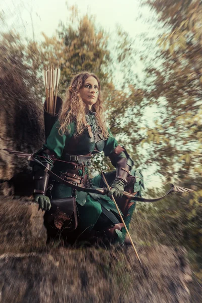 Elf woman in green leather armor with the bow and arrows on the — Stock Photo, Image