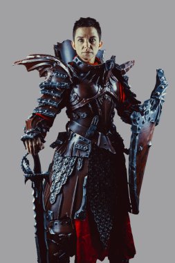 Elinde kılıç ve kalkanla ortaçağ kadın şövalyesinin portresi. Gri arkaplan üzerinde izole.