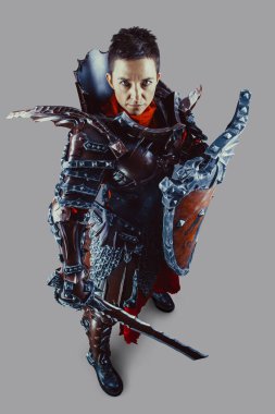 Elinde kılıç ve kalkanla ortaçağ kadın şövalyesinin portresi. Gri arkaplan üzerinde izole.