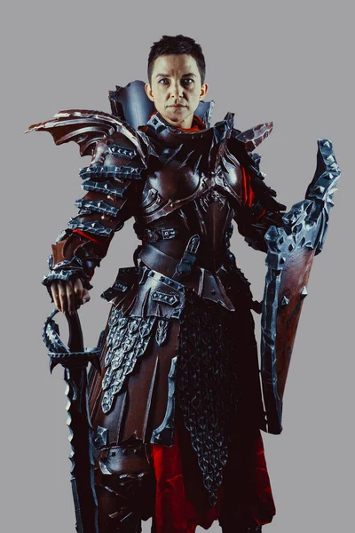 Elinde kılıç ve kalkanla ortaçağ kadın şövalyesinin portresi. Gri arkaplan üzerinde izole.