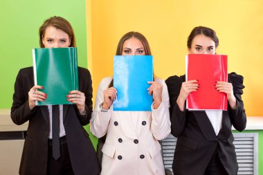 Ofiste elinde dosyalarla bekleyen üç kadın..