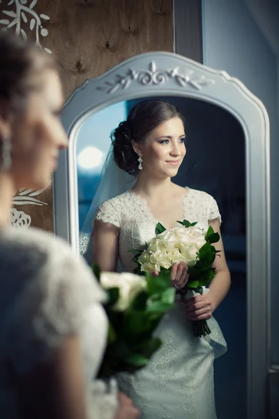 Mooie bruid met het boeket in de buurt van de miror. — Stockfoto
