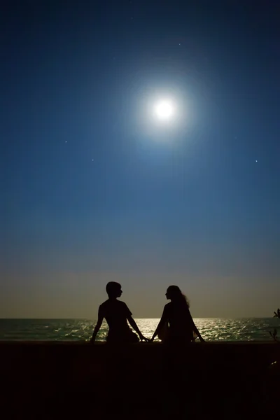 Yong pareja está sentado bajo la luna y las estrellas en el tropical — Foto de Stock