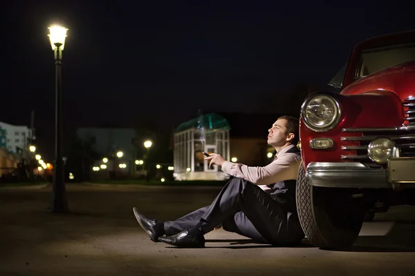 Smoking driver with the cigar is sitting near the vintage car. — Stock Photo, Image