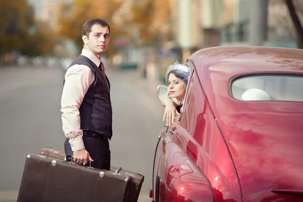 Casal bonito com a bagageira perto do carro vintage — Fotografia de Stock