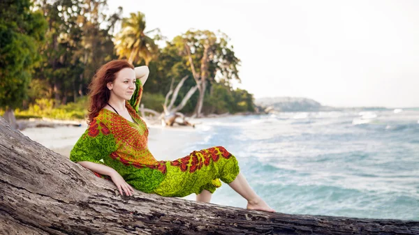 Beautiful woman in indian bright dress is sitting on the snag on — Stock Photo, Image