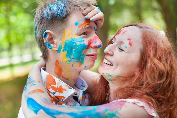 Laughing happy couple all in paint on the green background — Stock Photo, Image