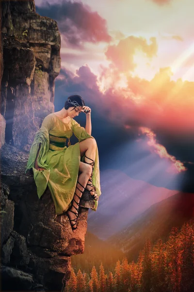 La solitaria y triste princesa está sentada en la roca. Puesta de sol montañas en — Foto de Stock
