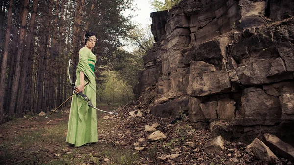Elf žena s kouzelnou luk na pozadí lesa. — Stock fotografie