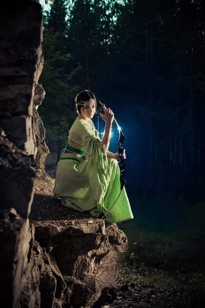 Mujer elfa con el arco mágico en el fondo de las rocas . — Foto de Stock