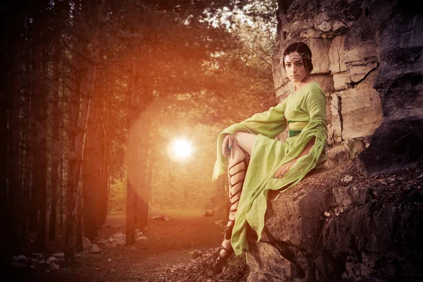 Ξωτικό γυναίκα κάθεται πάνω στα βράχια. Δάσος για το ιστορικό. — Φωτογραφία Αρχείου
