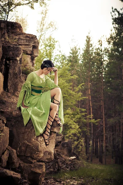 Lonely sad princess is sitting on the rock. Forest on the backgr — Stock Photo, Image