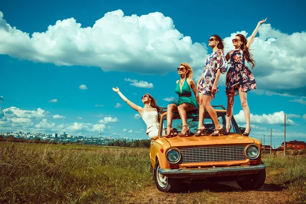 Quatro mulheres bonitas estão dançando no carro velho. Campos verdes em — Fotografia de Stock