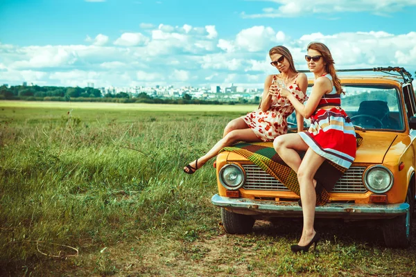 Duas mulheres bonitas no piquenique estão bebendo vinho no carro . — Fotografia de Stock