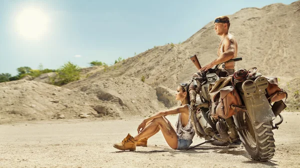 Sexy couple of bikers with guns on the desert background. — Stockfoto