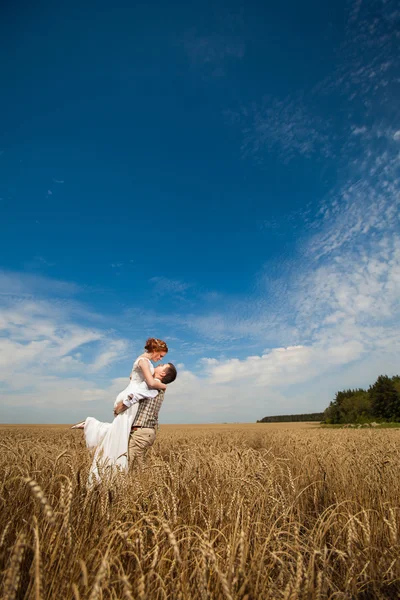 Glücklich umarmendes Paar auf dem Hintergrund des Weizenfeldes. — Stockfoto