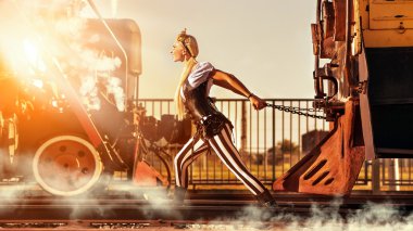 Sarışın kadın steampunk giysili bir retro tren çekiyor