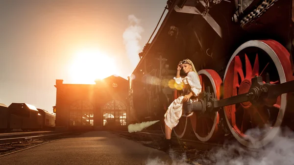 Mulher no vestido vintage está sentado na roda da locomotiva — Fotografia de Stock