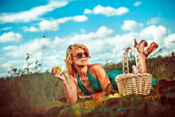 Sexy blond woman with the apple on the picnic. — Stock Photo, Image