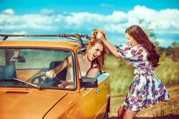 Uma mulher está a tentar tirar outra do carro. . — Fotografia de Stock