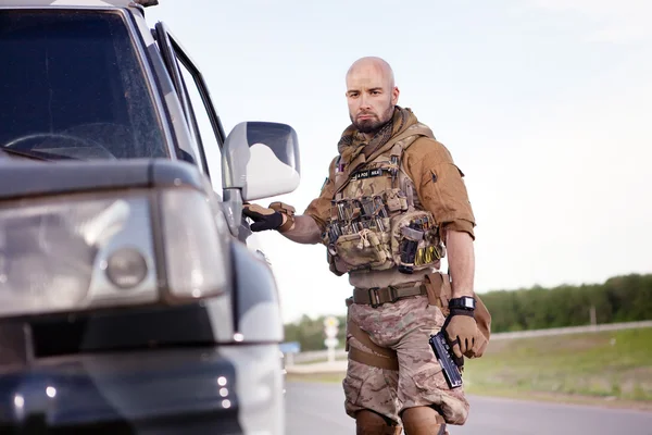 Soldado com a arma em uniforme americano perto de SUV militar . — Fotografia de Stock