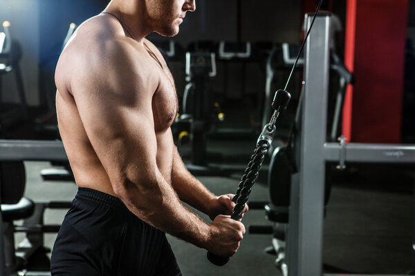 Powerful man with muscular build is training in the gym