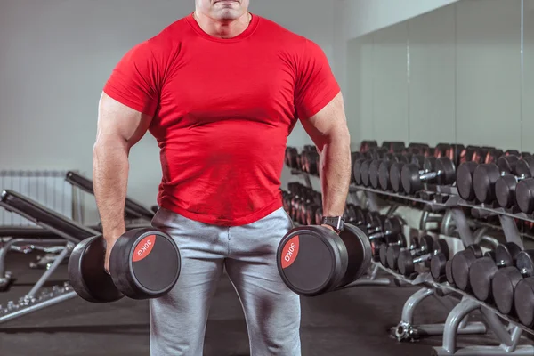 Uomo potente con corporatura muscolare si allena con i manubri — Foto Stock