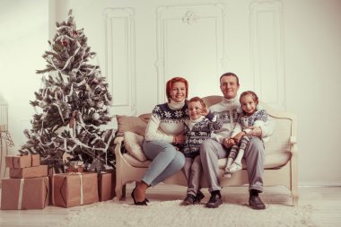 Güzel aile Noel ağacı yakınındaki kanepede oturuyor.