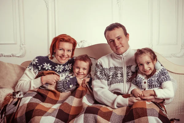 Bella famiglia in maglioni è sdraiato sul divano sotto il — Foto Stock