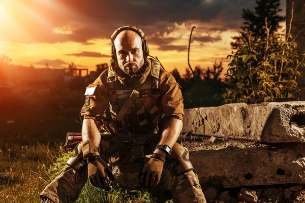 American soldier with the M4 rifle is having a rest. Sunset on t — Stock Photo, Image