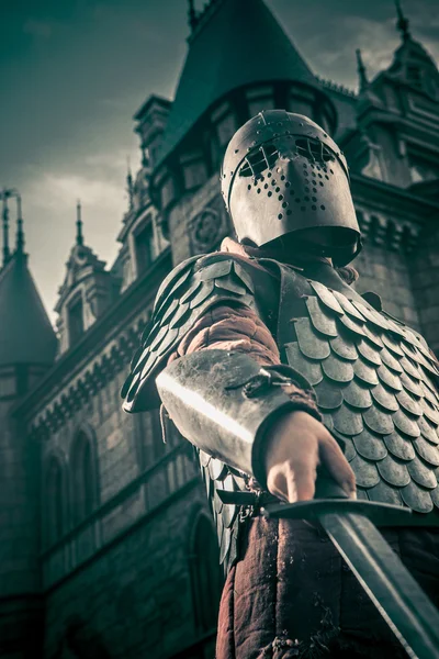 Medieval knight with the sword on the ancient castle background. — Stock Photo, Image