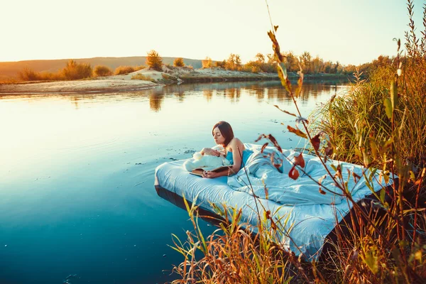 Hübsche Frau liegt auf dem schwimmenden Bett und liest ein Buch. s — Stockfoto
