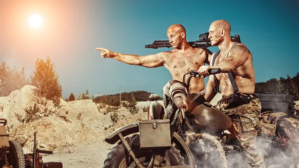Dos poderosos ciclistas calvos con armas en el fondo del desierto . — Foto de Stock