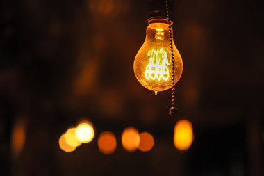 Koyu arka plan üzerinde parlayan Edison'un ampul.