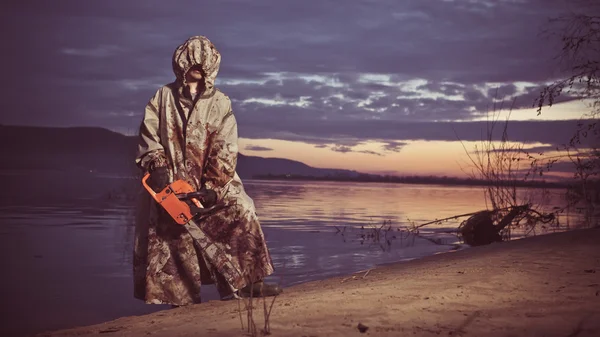 Maniac with the chainsaw on the sunset background. — Stock Photo, Image