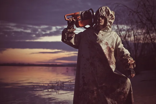 Maniac with the chainsaw on the sunset background. — Stock Photo, Image