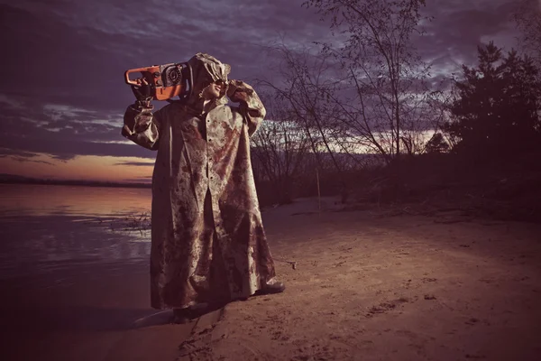 Maniac with the chainsaw on the sunset background. — Stock Photo, Image