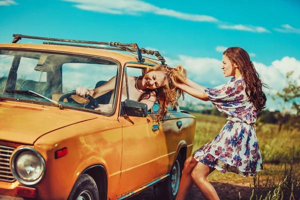 One woman is trying to pull another out of the car. — Stock Photo, Image