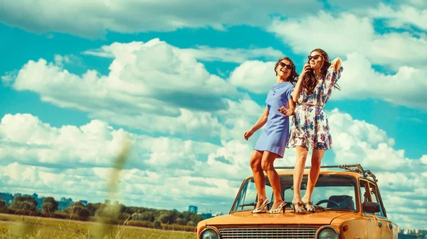 Dos hermosas mujeres están bailando en el coche viejo . — Foto de Stock