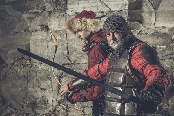 Old knight with the sword is protecting his squire