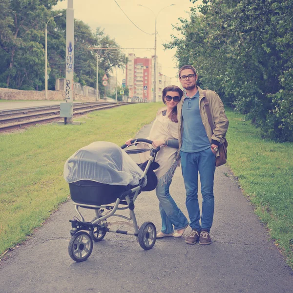 Родители ходят с детской коляской — стоковое фото