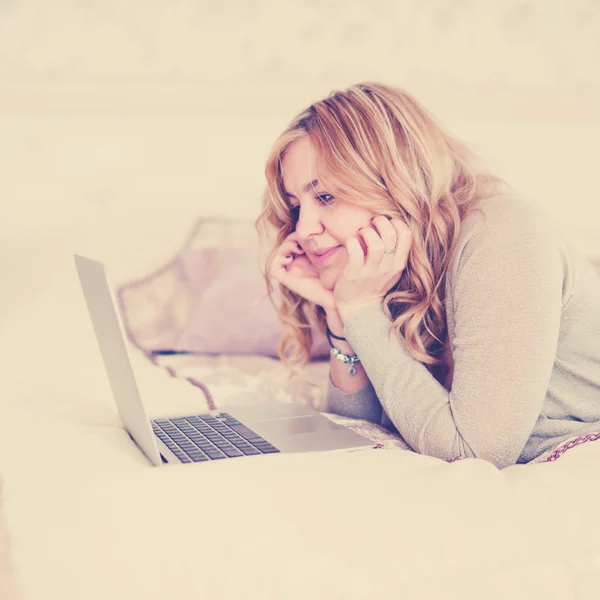 Woman with laptop on bed — Stock Photo, Image